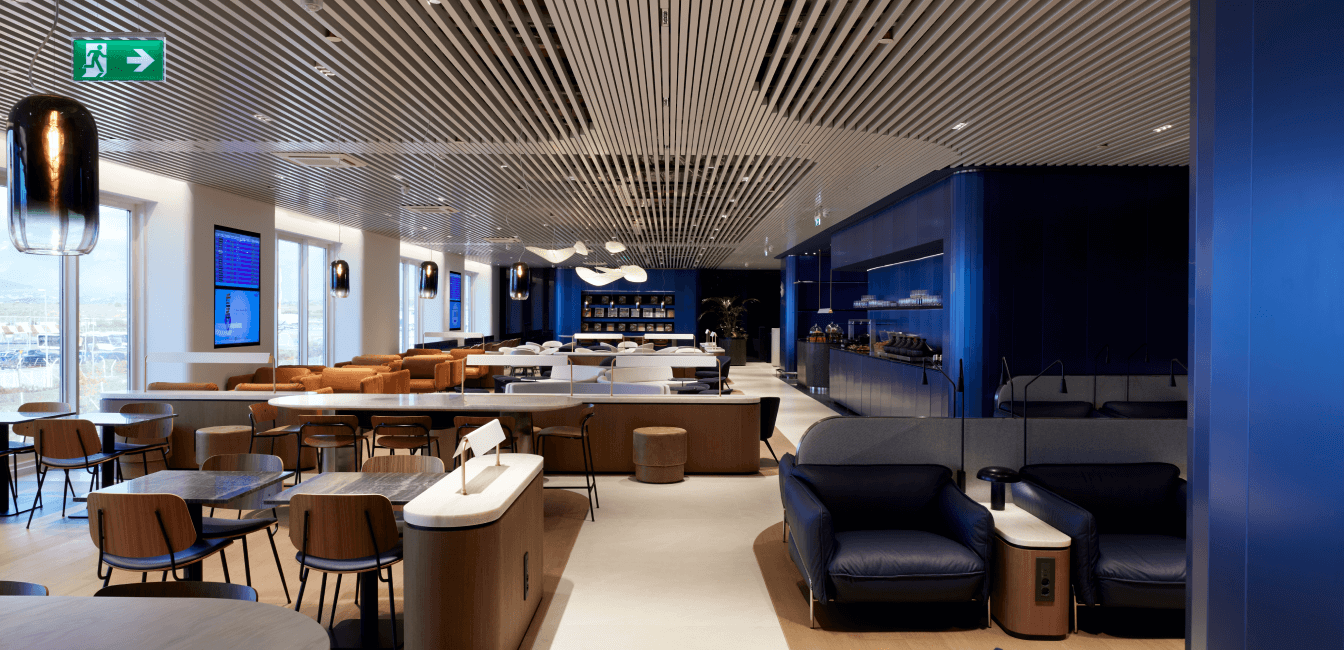 Χώρος business lounge με τραπέζια, καρέκλες και μεγάλα παράθυρα