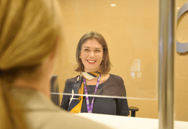 Employee at information kiosk serving traveller in Athens International Airport